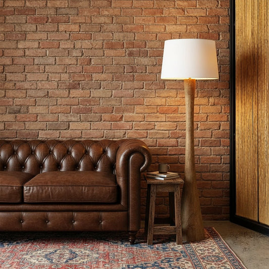 Floor lamp with a white shade next to a white sofa against a textured wall.