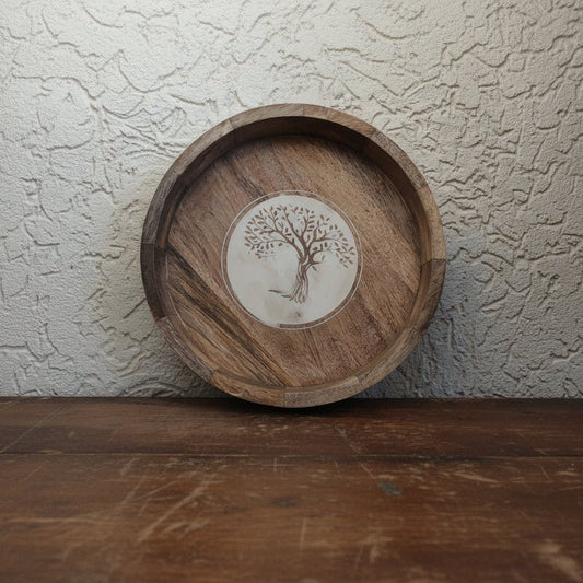 Wooden tray with tree design in the center on a textured wall background