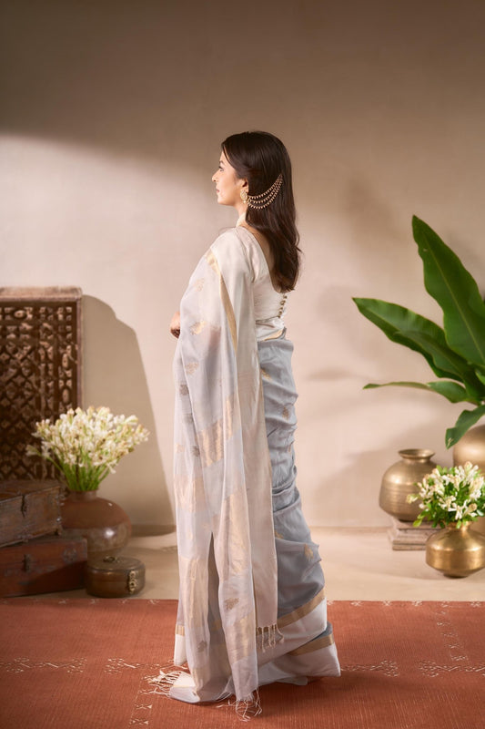 Woman in a light blue saree standing in a room with decorative elements.