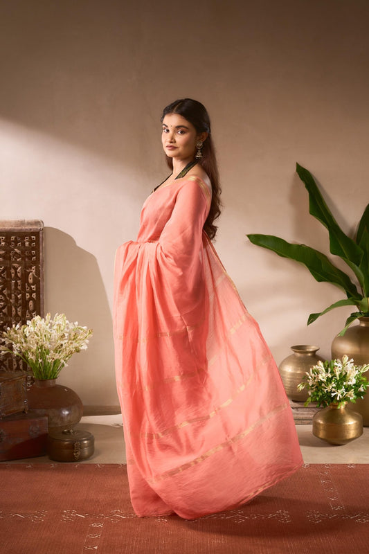 Woman in a pink dress standing in a decorative indoor setting with plants and vases.