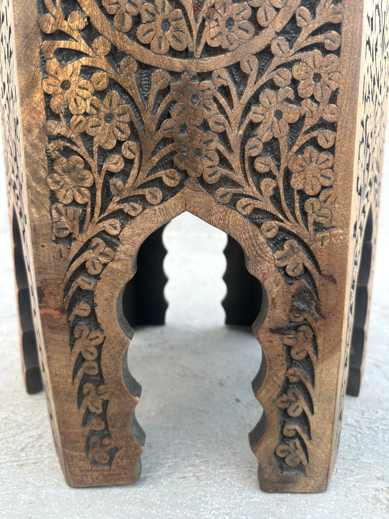 Wooden block with intricate floral carvings on a white background