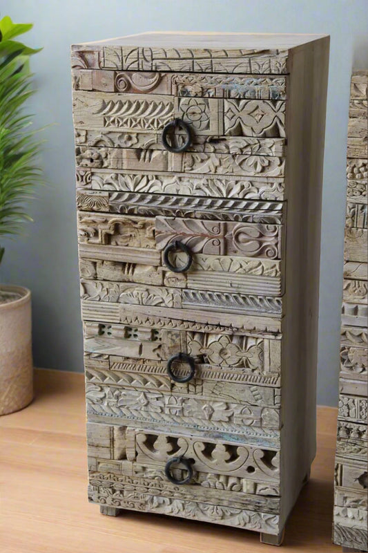 Wooden dresser with intricate carvings against a white brick wall.