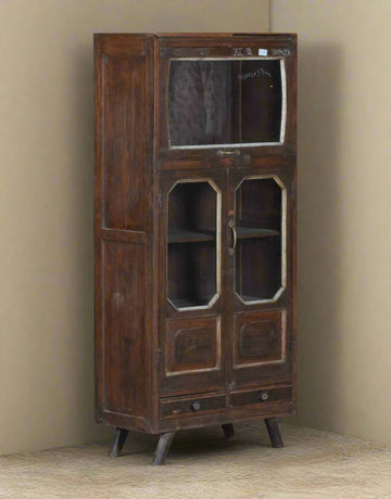 Vintage wooden cabinet with glass doors against a beige wall.