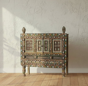 Decorative wooden chest with geometric patterns on a stone floor.