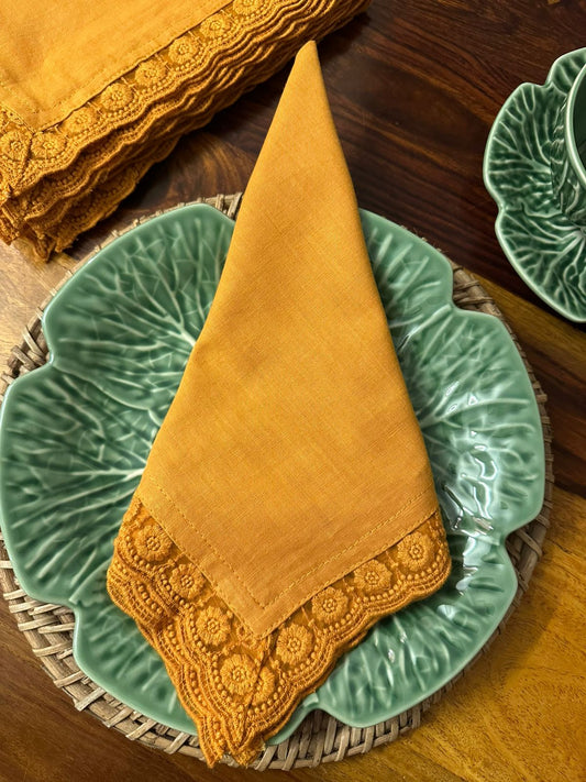 Mustard yellow napkin with lace trim on a green ceramic plate