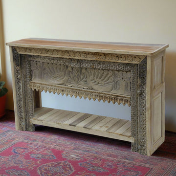 Wooden console table with intricate carvings on a patterned rug