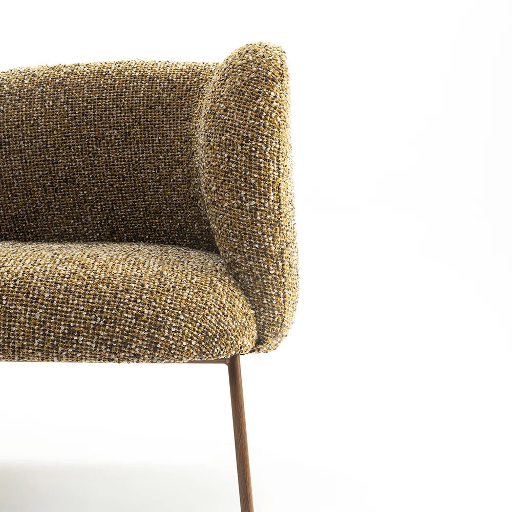 Its gracefully curved backrest and slender metal legs create a lightweight, sculptural silhouette — ideal for reading nooks, living rooms, or quiet corners.