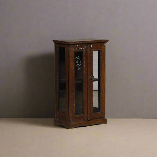 Small wooden cabinet with glass doors on a plain background