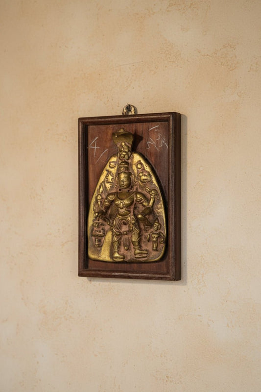 Brass plaque of a deity on a wooden frame
