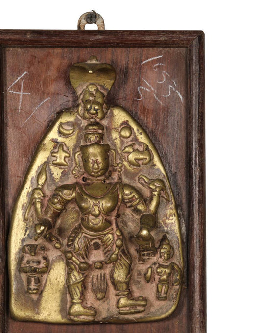 Brass plaque with intricate designs on a wooden frame