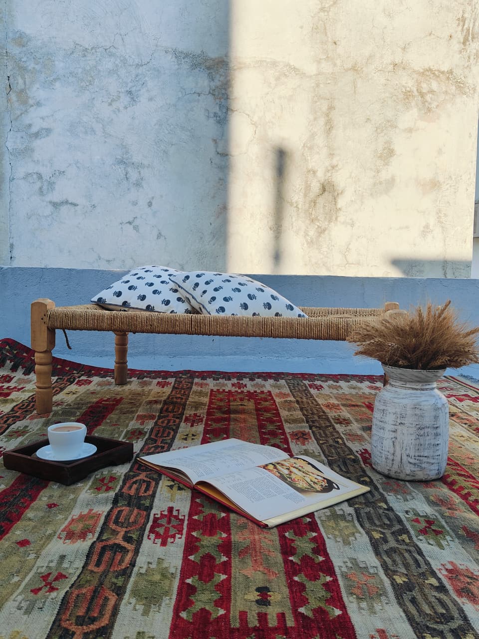 Rustic interior with a woven bench, patterned rug, and decorative items.