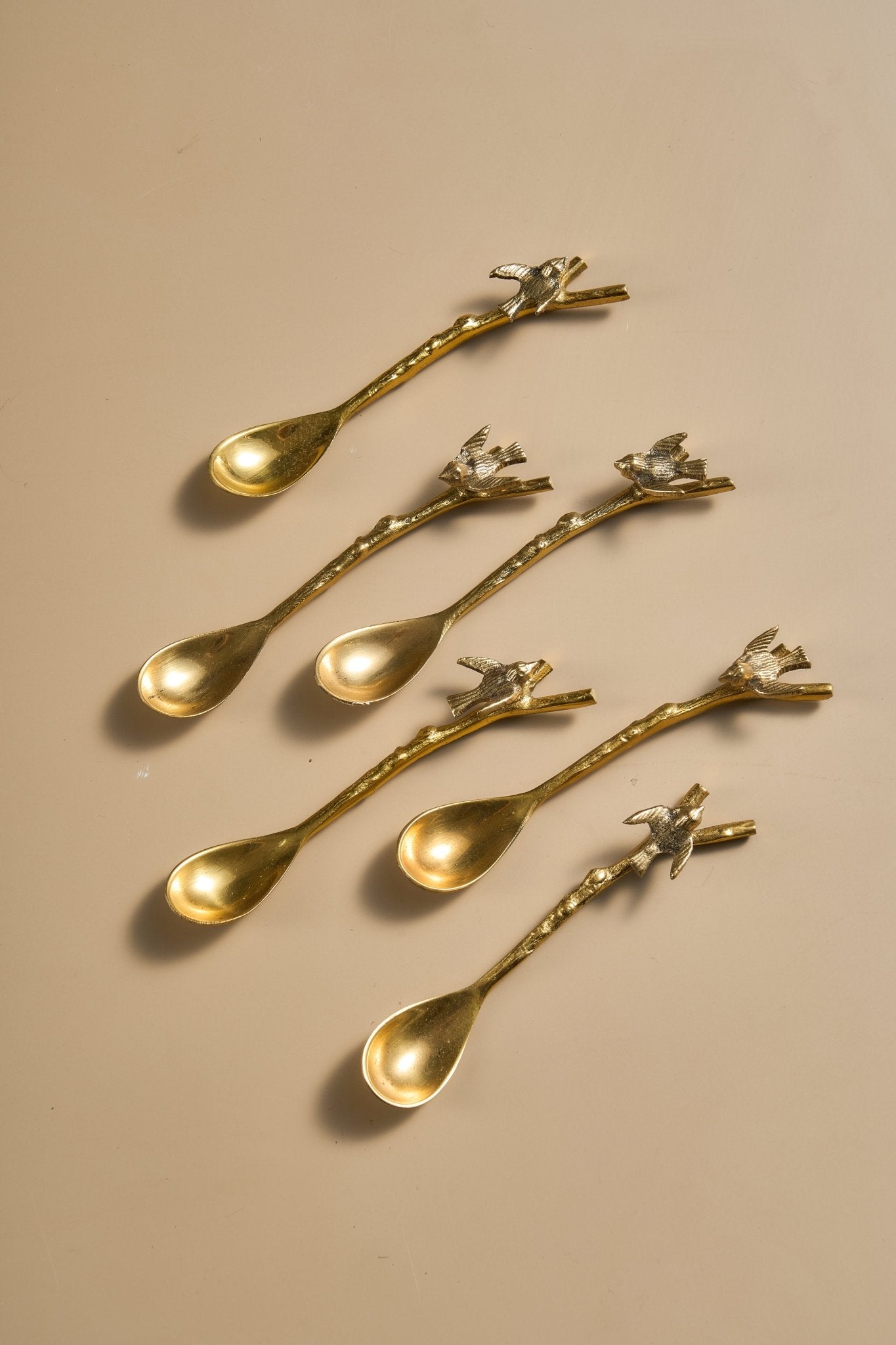 Set of gold spoons with decorative handles on a beige background