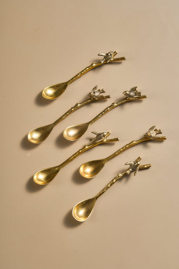 Set of gold spoons with decorative handles on a beige background