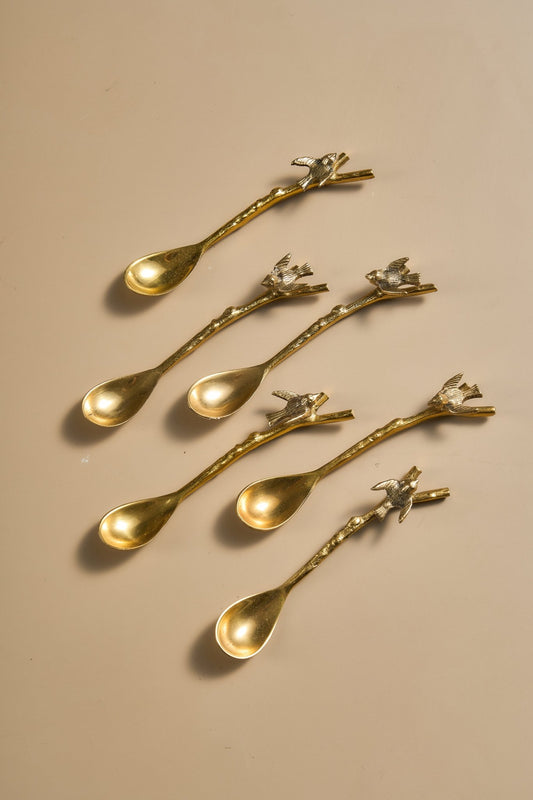 Set of gold spoons with decorative handles on a beige background