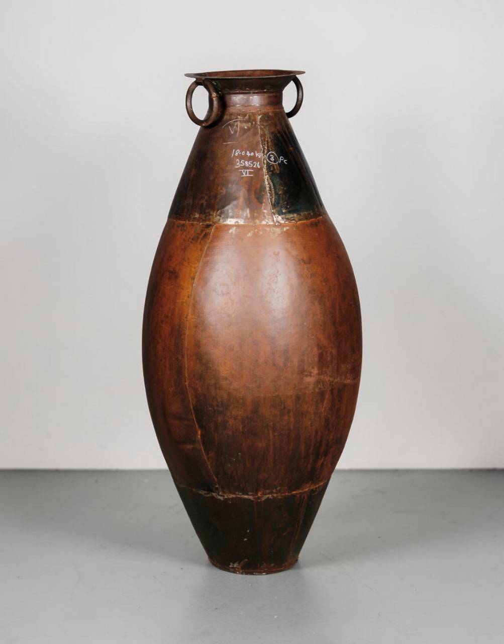 Brown ceramic vase with black accents on a gray surface and light gray background