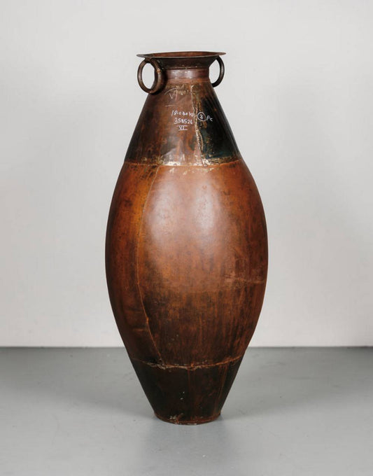 Brown ceramic vase with black accents on a gray surface and light gray background