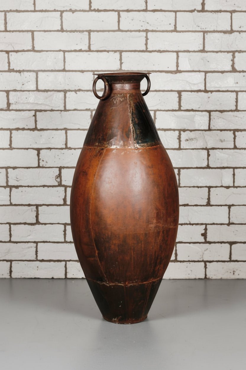 Brown ceramic vase with black accents on a gray surface and light gray background