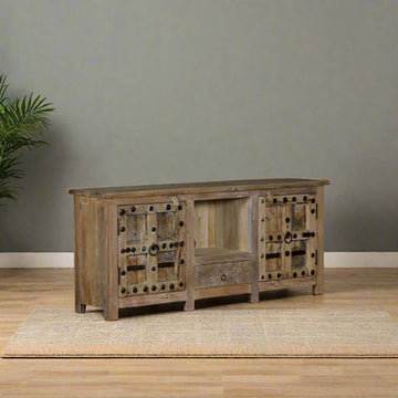 Wooden sideboard against a plain wall with a plant on the left.