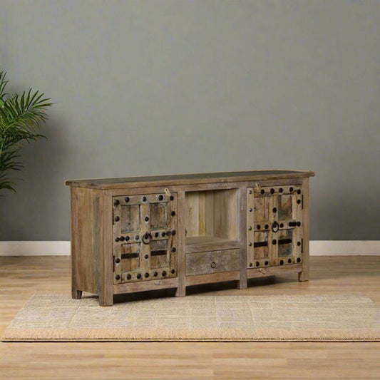 Wooden sideboard against a plain wall with a plant on the left.