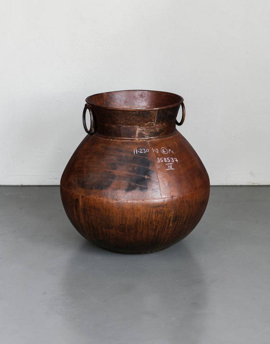 Brown ceramic jar with handles on a gray surface and white background