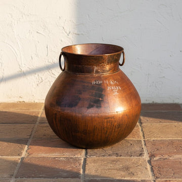 Brown ceramic jar with handles on a gray surface and white background