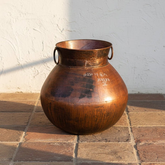 Brown ceramic jar with handles on a gray surface and white background