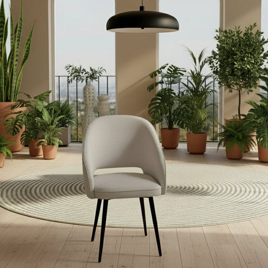 Gray chair with black legs in a room with plants and large windows.