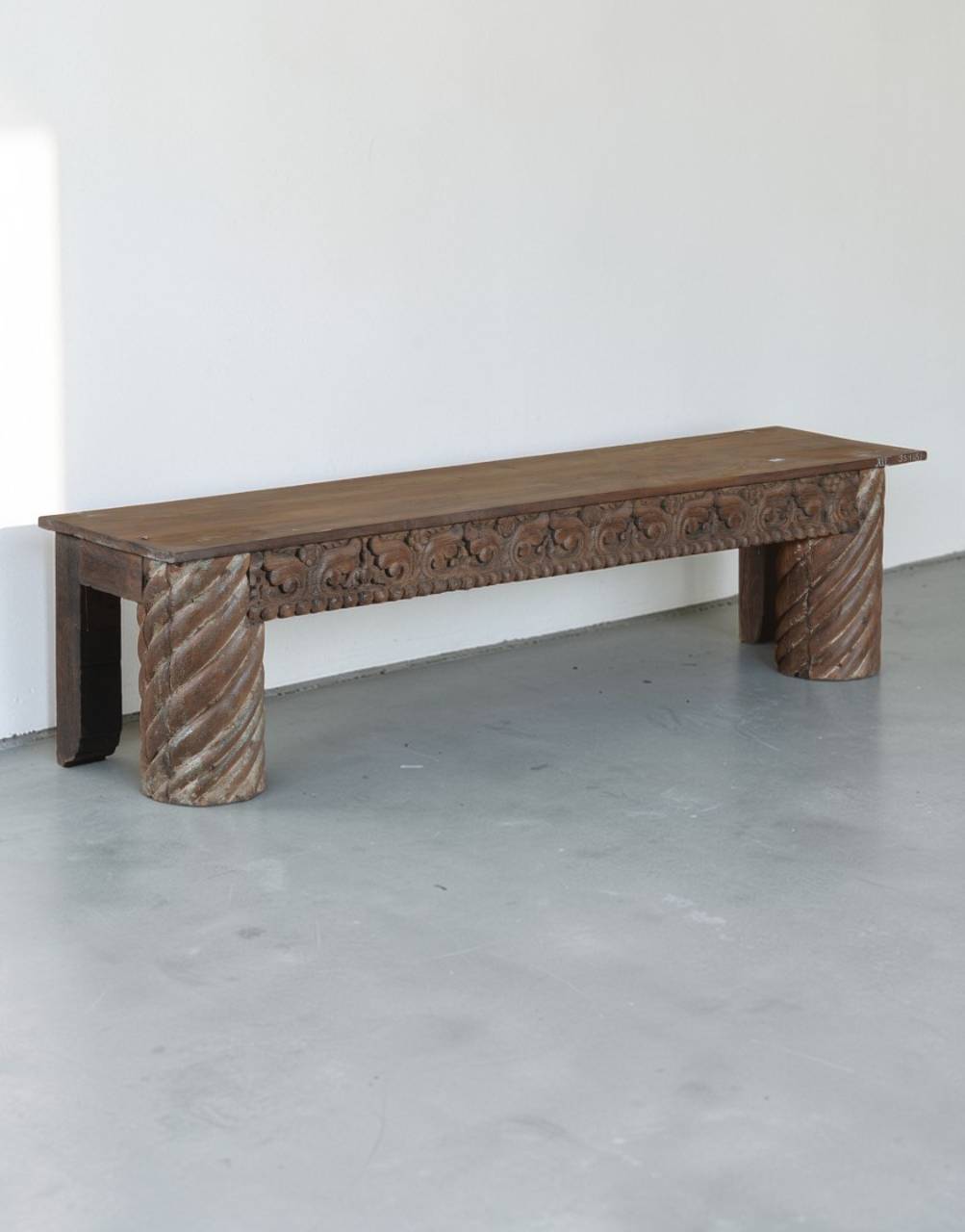 Wooden bench with textured legs in a minimalistic room