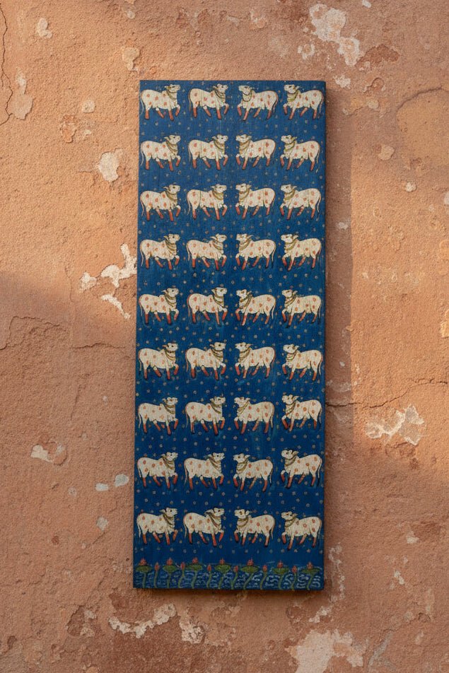 Decorative panel with cow pattern on a blue background, mounted on a wall.