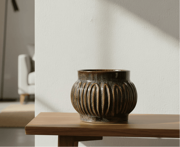 Decorative ceramic vase on a wooden table with a blurred room background
