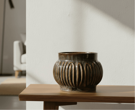 Decorative ceramic vase on a wooden table with a blurred room background