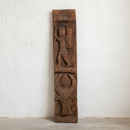 Wooden panel with carvings of a figure and a bull on a white background