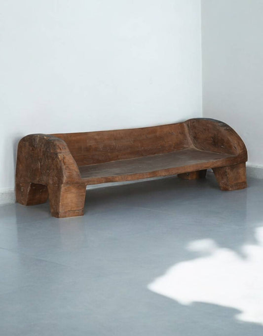 Wooden bench against a white wall on a gray floor