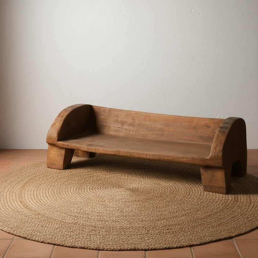 Wooden bench against a white wall on a gray floor
