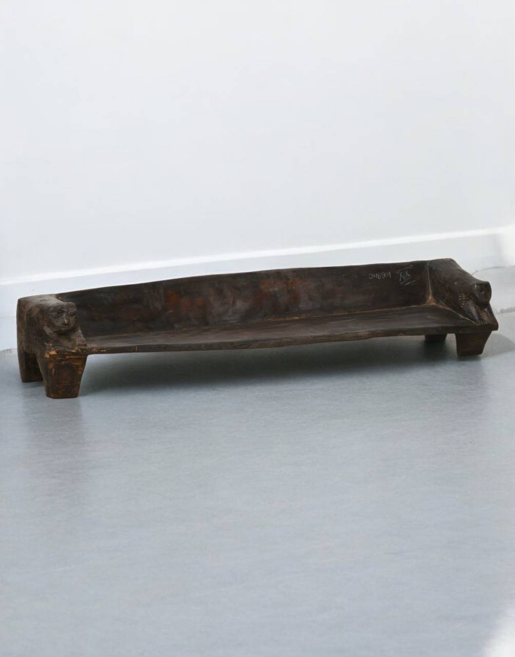 Wooden bench on a gray floor with a white wall background