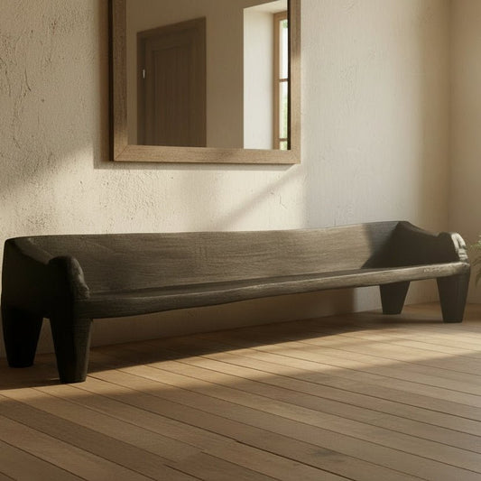 Long black stone bench on a light wooden floor with a white wall background