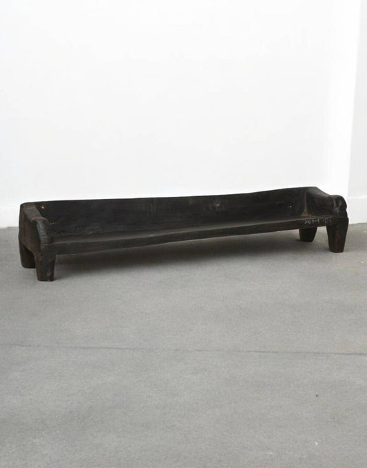 Black wooden bench on a gray floor with a white wall background
