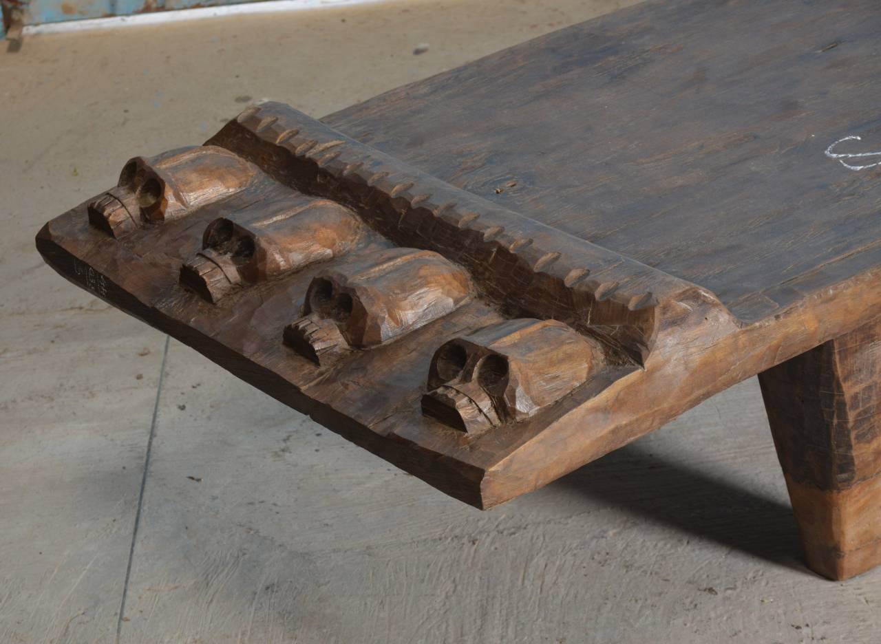 Wooden bench with carved design on a concrete floor