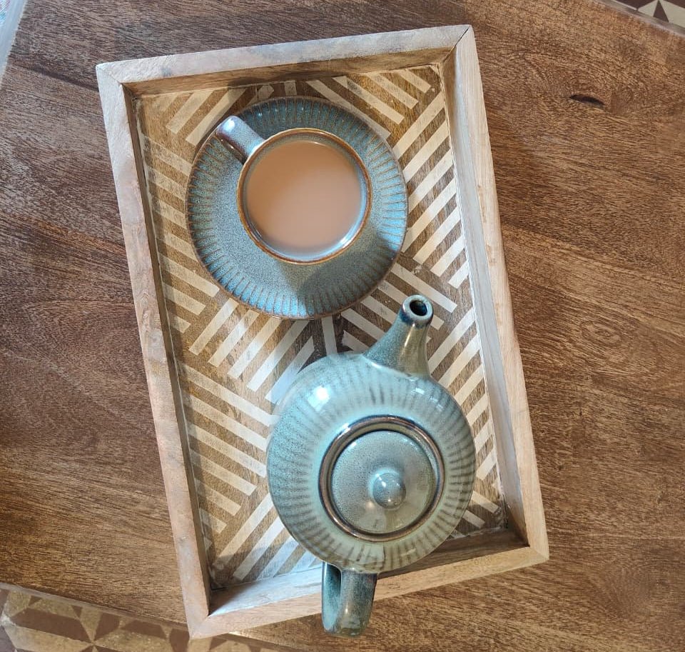 Tea set with cup and teapot on a decorative wooden tray.