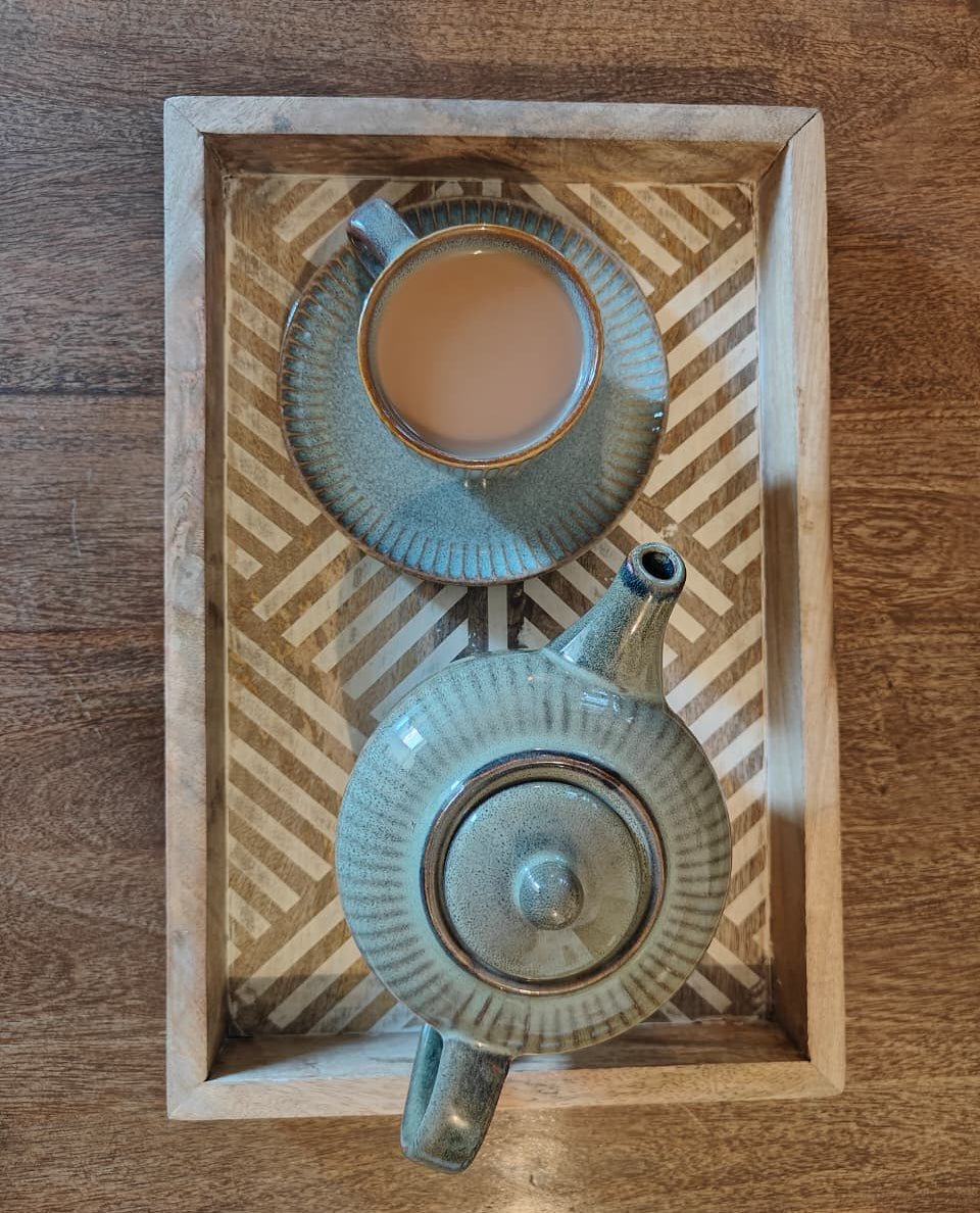 Tea set with a teapot and cup on a decorative wooden tray.