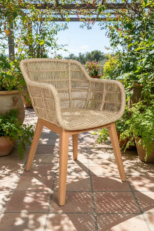 Wicker chair on a patio with plants and flowers in the background