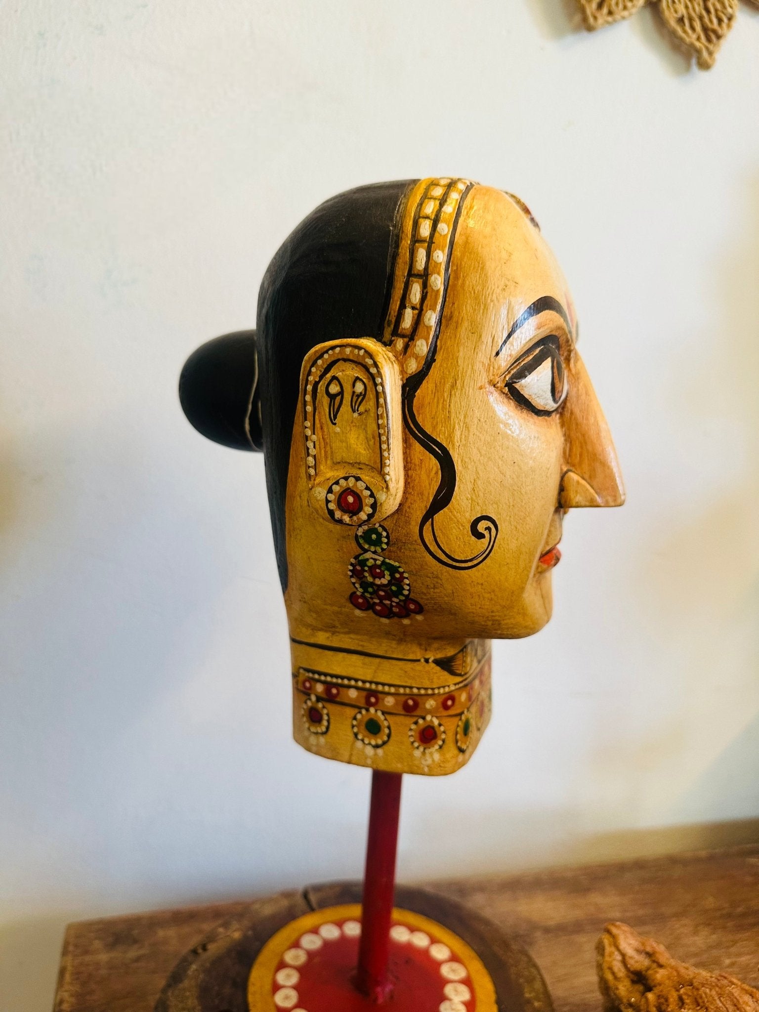 Decorative mask with intricate designs on a stand against a white background
