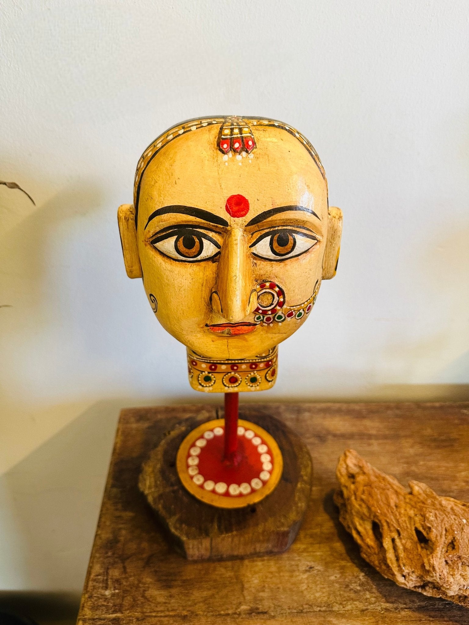 Decorative head sculpture on a wooden base with a plain background