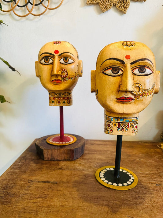 Decorative head sculpture on a wooden base with a plain background