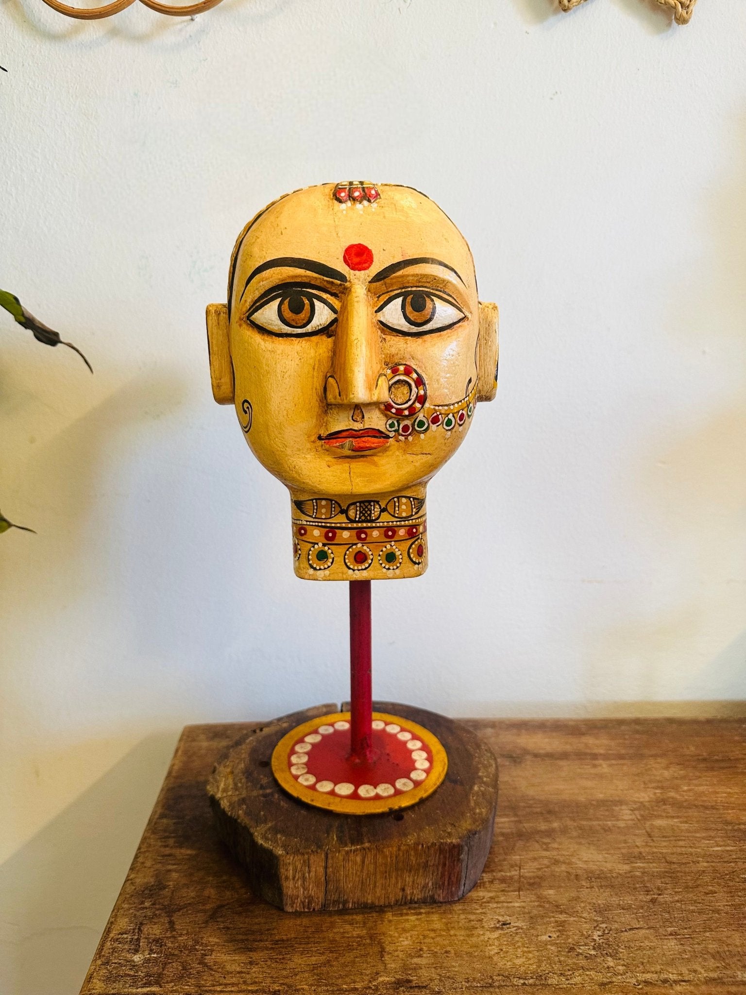 Decorative head sculpture on a wooden base with a plain background