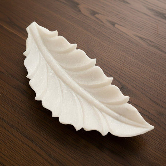 White leaf-shaped object on a dark marble surface