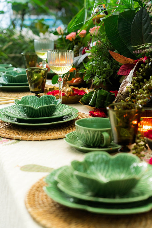 Green ceramic tableware on a table with a tropical setting