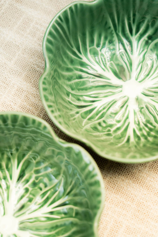 Two green ceramic plates with leaf pattern on a beige fabric background