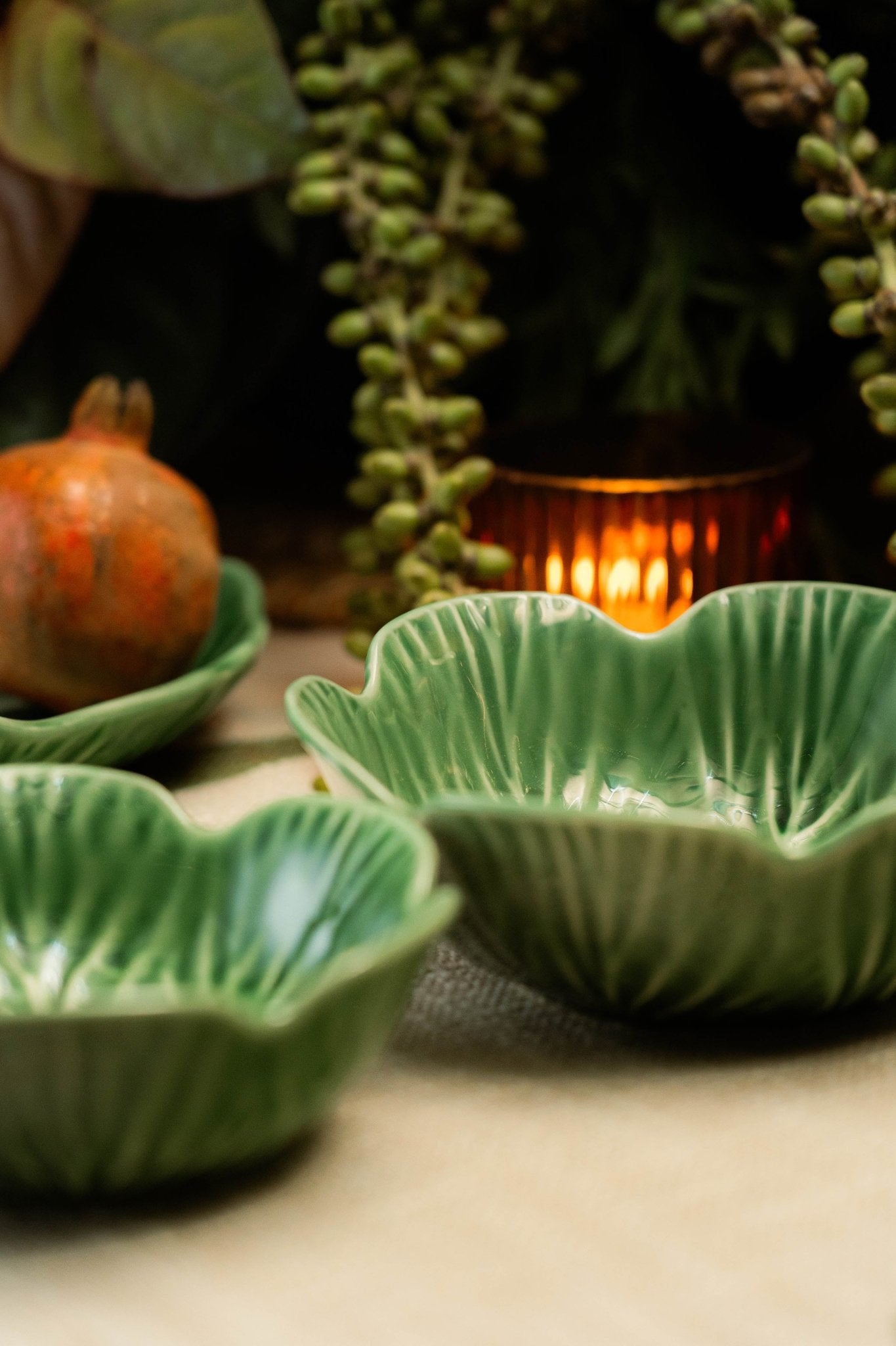 Green ceramic leaf-shaped bowls on a wooden surface with a warm light in the background.