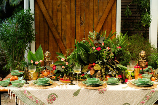 Decorative table setting with plants, flowers, and statues outdoors.
